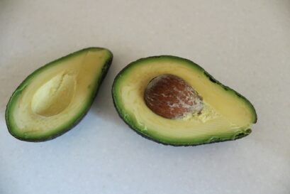 an avocado cut in half on a white surface