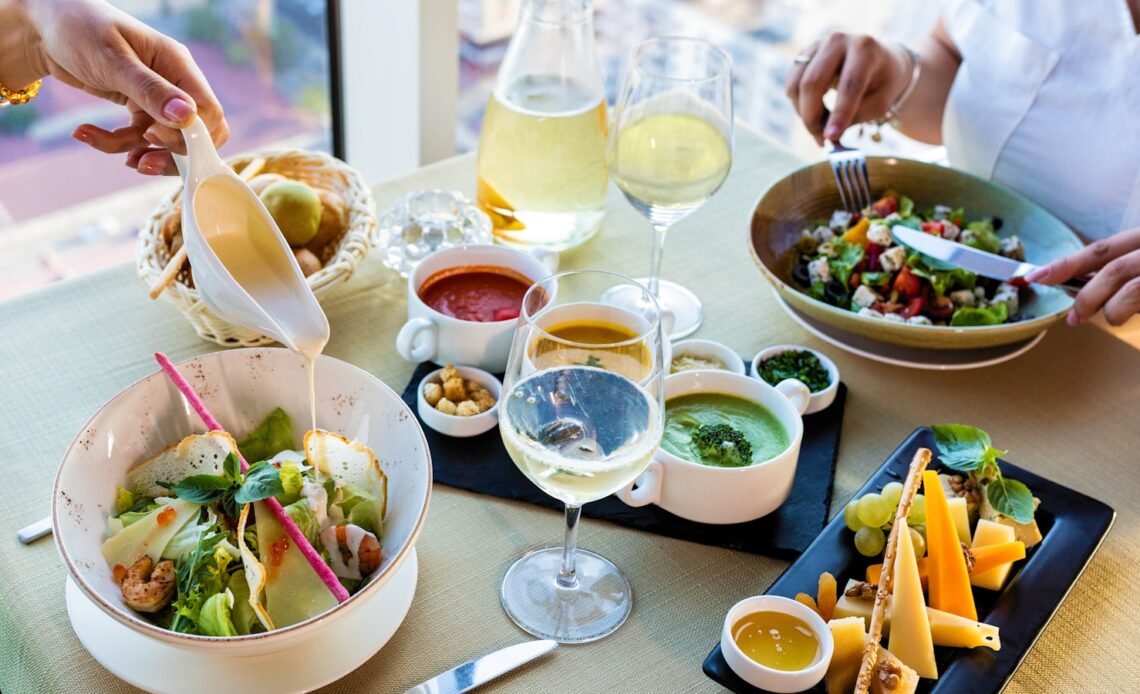 vegetable salad on white ceramic bowl beside clear wine glass